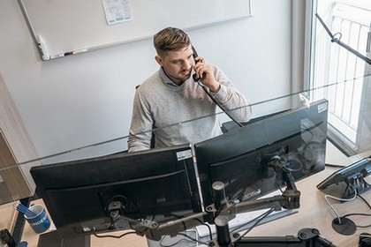 Ein junger Mann schaut auf seinen Computer, während er telefoniert