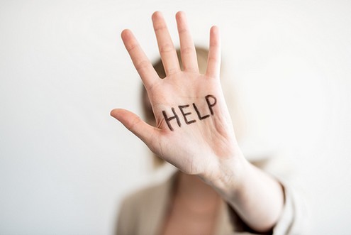 Eine Frau hält eine Hand hoch, auf der "help" geschrieben steht